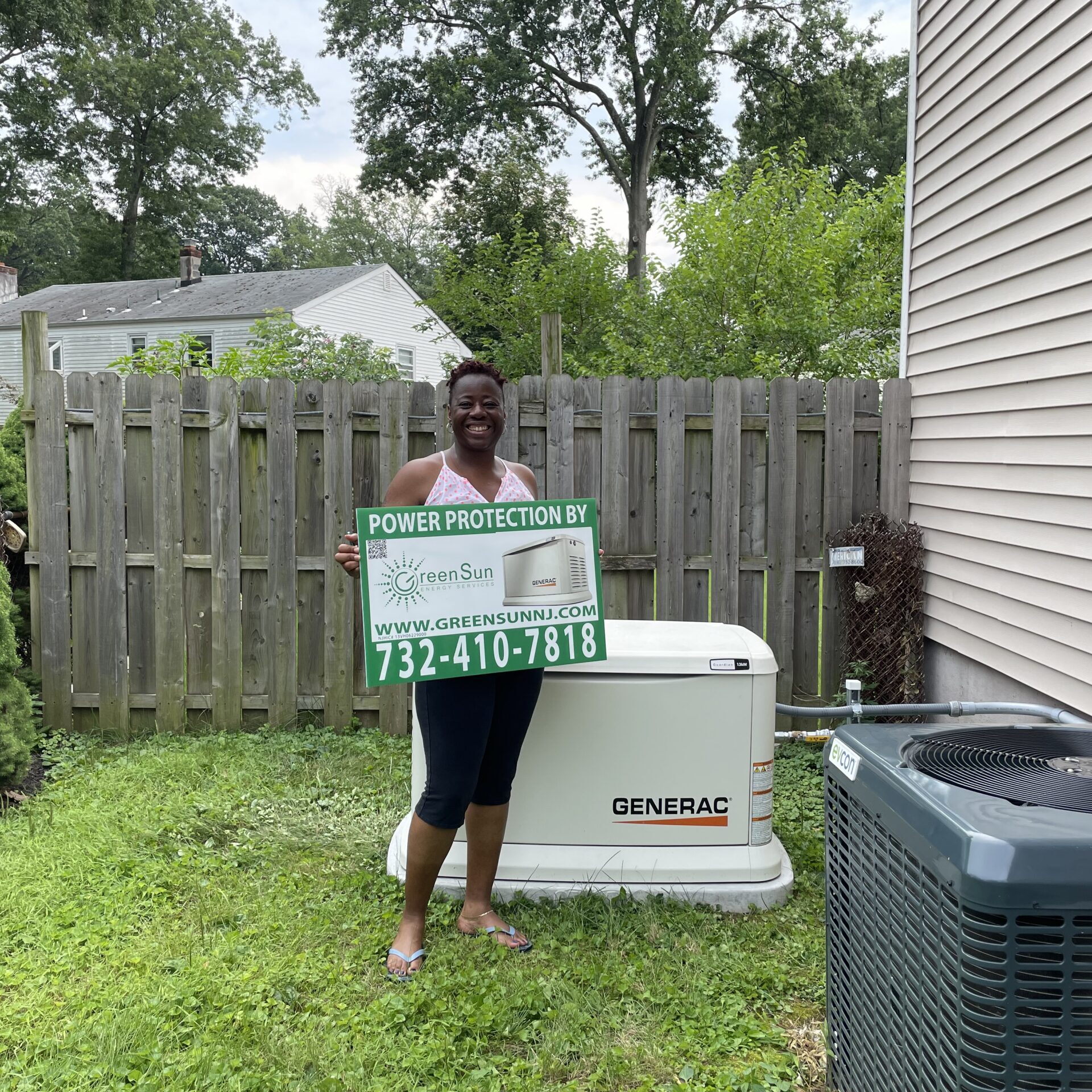 Piscataway NJ homeowner holding Green Sun Energy Services sign in front of newly installed Generac standby generator