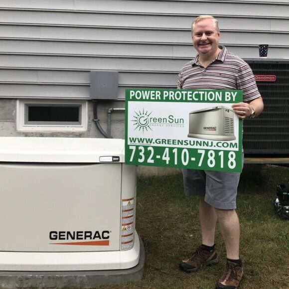 Manchester NJ homeowner holding Green Sun Energy sign in front of newly installed Generac standby generator