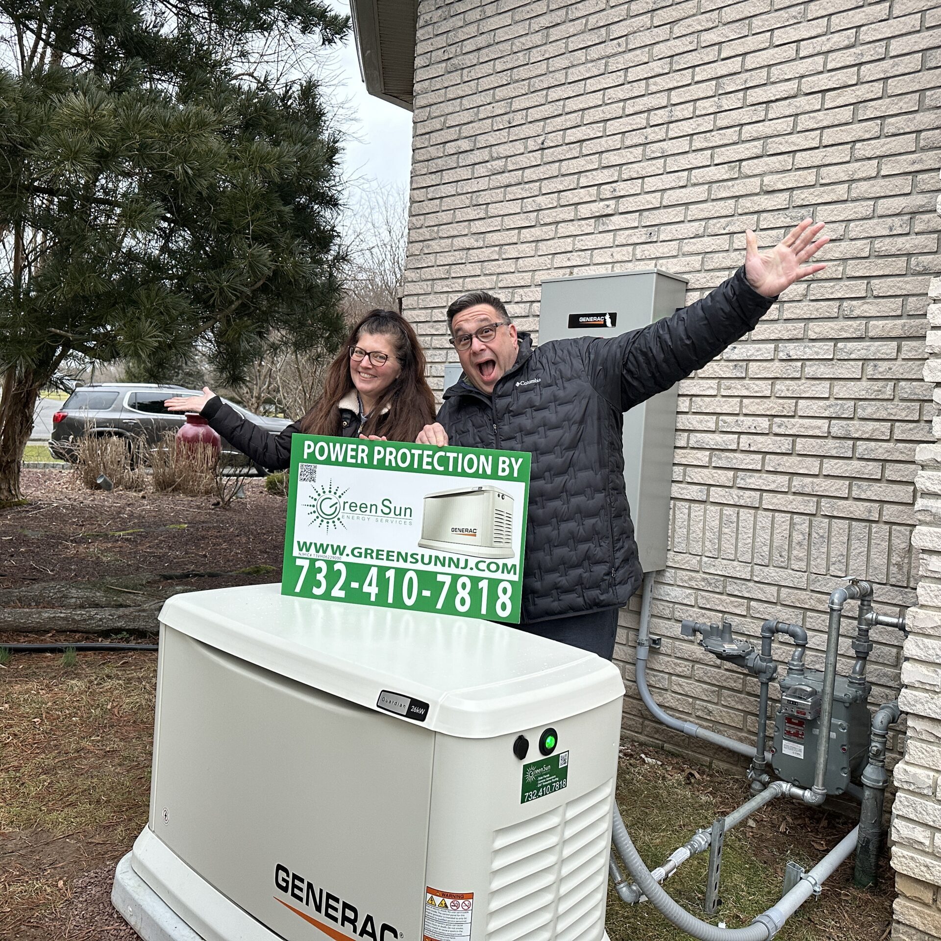 Clients holding Green Sun Energy Services, LLC lawn sign near their newly installed Generac home standby generator in Millstone NJ