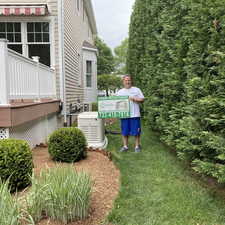 Client holding Green Sun Energy Services, LLC lawn sign near a newly installed Generac home standby generator in Little Silver, NJ.